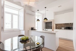 Eine moderne Küche mit weißen Schränken, einem Glastisch und einem eingebauten Backofen.