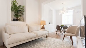 A modern living room with a sofa, a dining table with chairs, a lamp, and a television. - Your Lisbon Home Santa Apolónia (Lisbon)