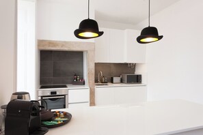 Eine moderne Küche mit Kochinsel, Backofen, Mikrowelle und Pendelleuchten.