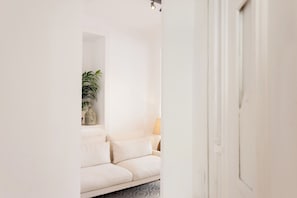 Ein Flur, der in einen Wohnbereich mit einer Couch und einer Lampe führt.