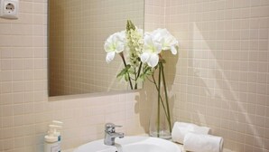 Un bany amb un lavabo, un mirall i un ram de flors.