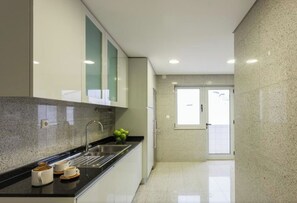 Cuina moderna amb taulell de granat, vàter d'acer inoxidable i finestra amb vidre mat.
