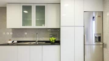 Una cocina moderna con armarios blancos, un refrigerador de acero inoxidable y una encimera de granito.
