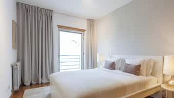 A hotel room with a bed, bedside lamps, a window with curtains, and a radiator.