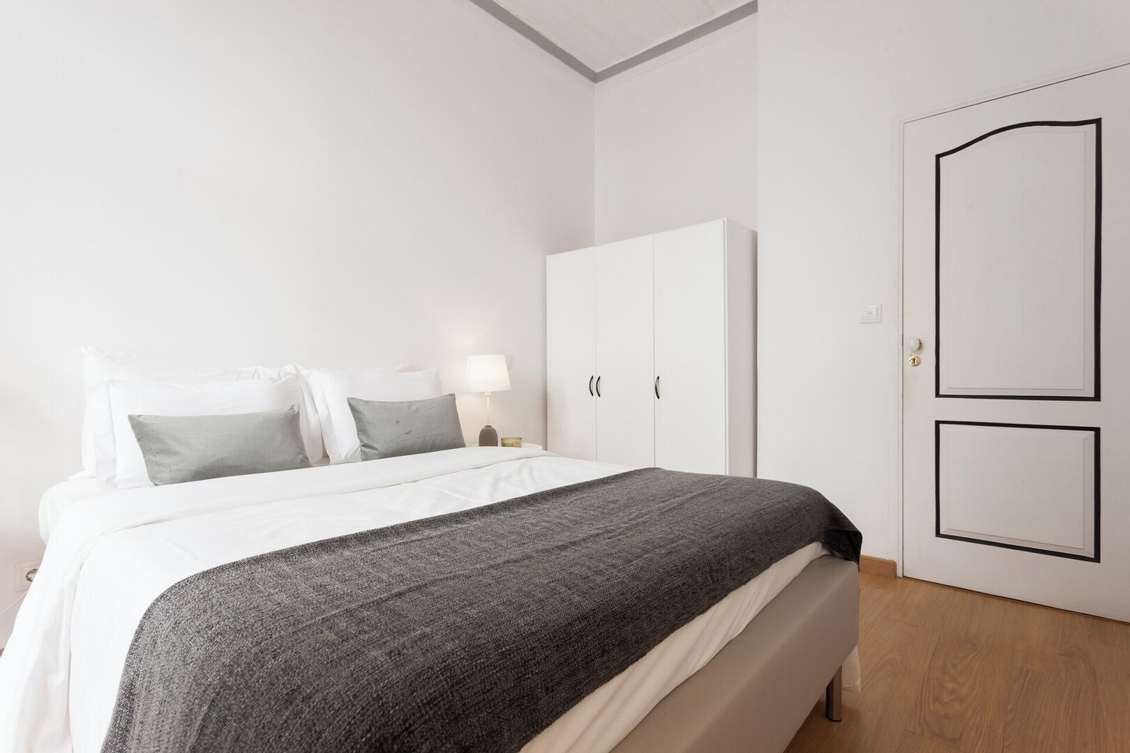Ein Schlafzimmer mit einem Bett, einem weißen Kleiderschrank und einer Tür.