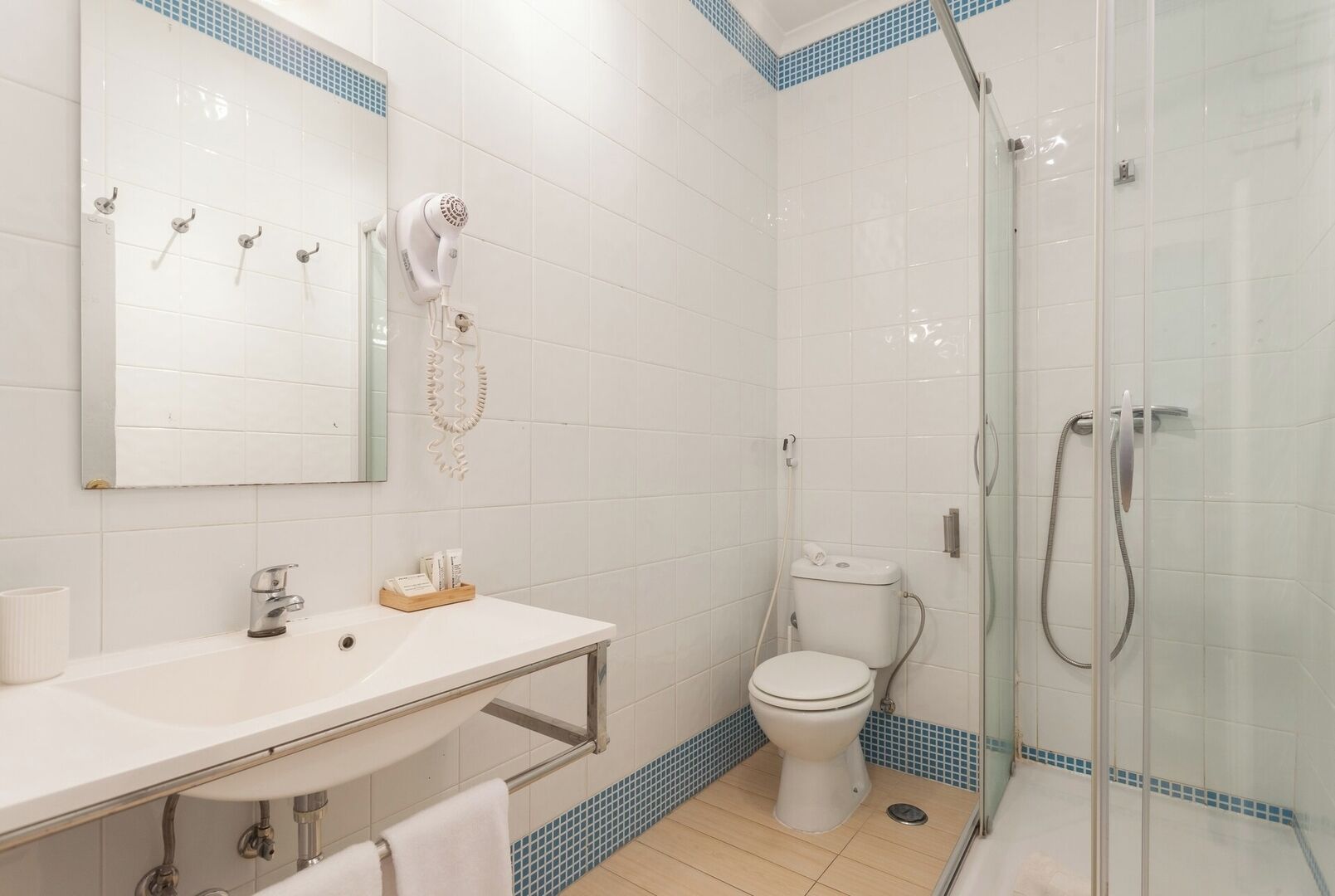 A bathroom with a white sink, a mirror, a toilet, and a glass-enclosed shower area.