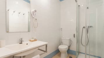 A bathroom with a white sink, a mirror, a toilet, and a glass-enclosed shower area.