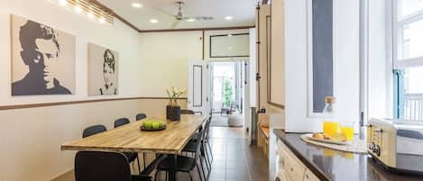 A modern kitchen with a built-in washing machine, a dining area with a long table and chairs, and artwork on the walls.