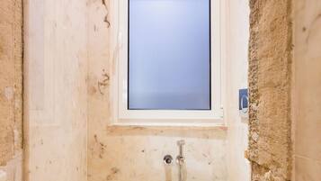 A bathroom with a toilet, a shower, and a window.