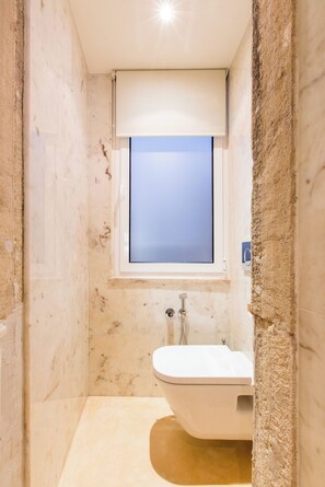 A bathroom with a toilet, a shower, and a window. - Living Bairro Alto III (Lisbon)