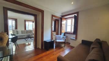 A spacious living area with hardwood flooring, a sofa, a chair, and a small table.
