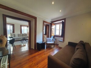 A spacious living area with hardwood flooring, a sofa, a chair, and a small table. - Living Bairro Alto III (Lisbon)
