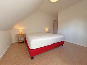 A bedroom with a single bed, two bedside tables with lamps, and a door. - Sunny Duplex Stay in City Center (Knokke-Heist)