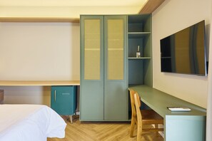 A hotel room with a bed, a desk, a wardrobe, and a television.