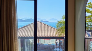 A view through a window with a tiled roof and a table and chairs outside. - VILLA NK SUITES (Ubatuba)
