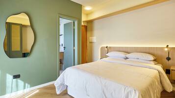 A bedroom with a bed, a mirror, a door, and a nightstand with a lamp.