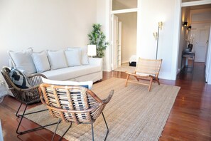 A living room with a sofa, two wicker chairs, a floor lamp, and a potted plant. - The Residences at Bairro Alto (Lisbon)