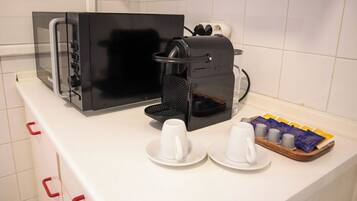 A kitchenette with a coffee maker, a toaster, and a tray with cups and coffee pods.