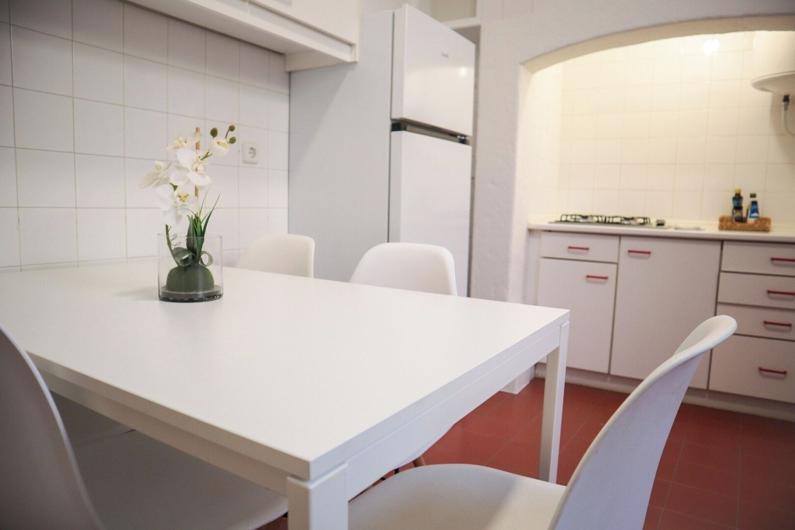 Une cuisine moderne avec des meubles blancs, une table à manger blanche et des chaises.