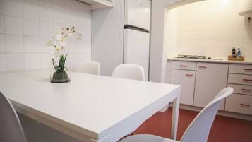 Une cuisine moderne avec des meubles blancs, une table à manger blanche et des chaises.