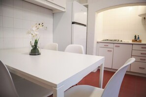 A modern kitchen with white cabinetry, a white dining table, and chairs. - The Residences at Bairro Alto (Lisbon)