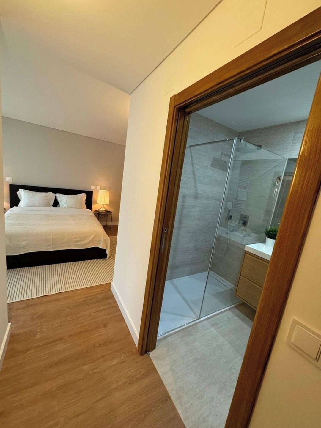 Une chambre à coucher comprenant un lit, une table de chevet et une douche séparée par des parois en verre.