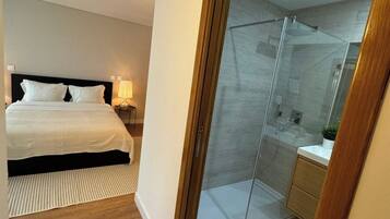 Une chambre à coucher comprenant un lit, une table de chevet et une douche séparée par des parois en verre.