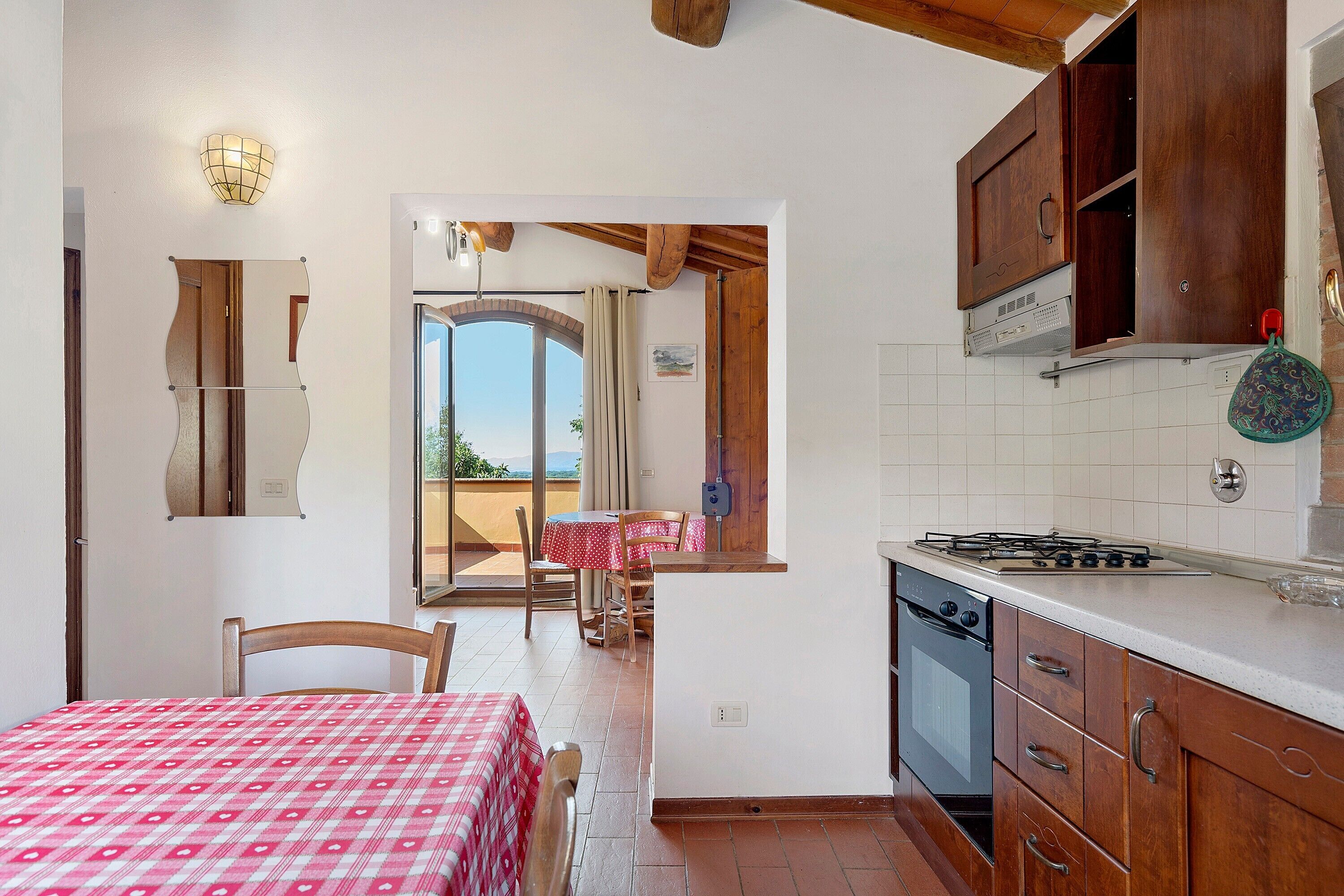 Una cocina compacta con estufa a gas, armarios de madera y un comedor con mesa y sillas.