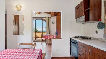 Una cocina compacta con estufa a gas, armarios de madera y un comedor con mesa y sillas.