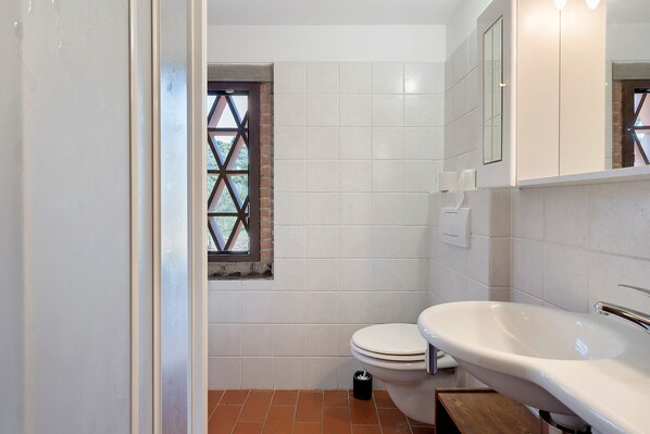A bathroom with a toilet, a sink, and a window with a diamond pattern.