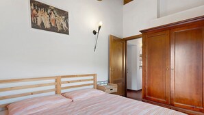 Una camera da letto con un letto in legno, un armadio e un quadro appeso al muro.