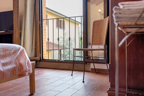 A room with a bed, a chair, a window, and a view of a building outside. - Apartment 'Appartamento Fienile' with Shared Garden, Wi-Fi and Air Conditioning (Terranuova Bracciolini)