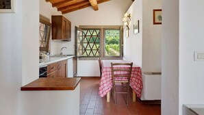 Una cucina con mobili in legno, un lavandino e una finestra che si affaccia sul verde.