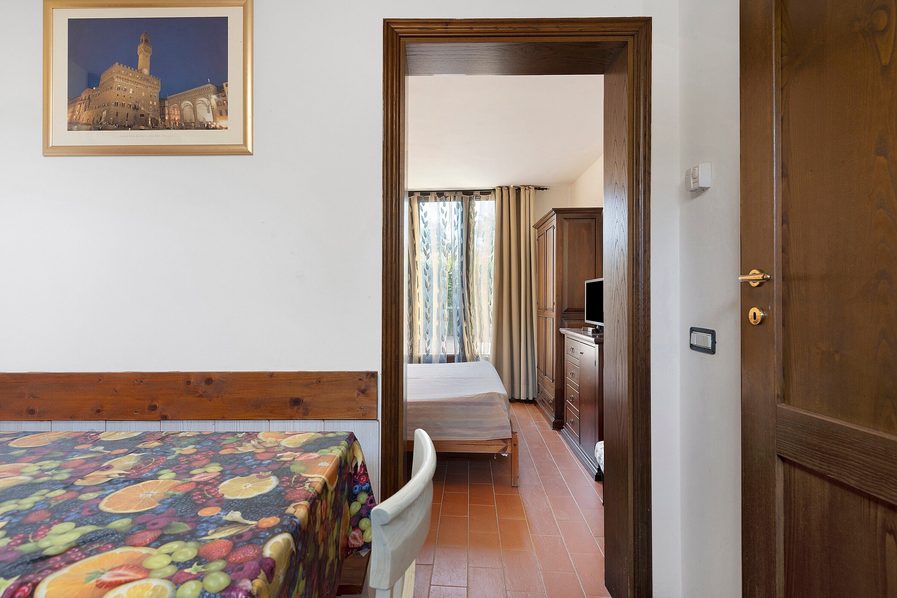 Ein Hotelzimmer mit einem Bett, einem Sessel, einem Schreibtisch und einem Fernseher.