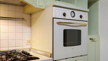 Une cuisine avec un fourneau blanc, un brûleur à gaz et un four blanc.