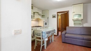 Un espace de vie compact comprenant un coin cuisine, un coin repas avec une table et des chaises, et un canapé.