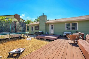 A green house with a trampoline, a barbecue grill, and a wooden deck. - Suncrest Rise! Family Escape Near Fort Carson (Colorado Springs)