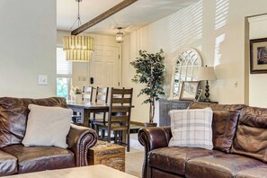 A living room with leather sofas, a dining table, and chairs. There is a large potted plant and a lamp on a side table. - Suncrest Rise! Family Escape Near Fort Carson (Colorado Springs)