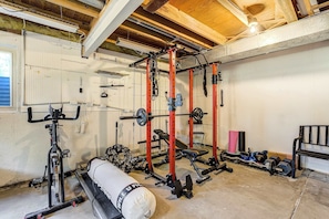 A gym with various exercise equipment, including a squat rack, bench press, and weight plates. - Suncrest Rise! Family Escape Near Fort Carson (Colorado Springs)