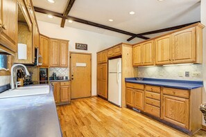 A kitchen with wooden cabinets, a stainless steel sink, and a refrigerator. - Suncrest Rise! Family Escape Near Fort Carson (Colorado Springs)