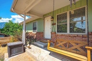 A porch with a wooden swing, a potted plant, and a mailbox. - Suncrest Rise! Family Escape Near Fort Carson (Colorado Springs)