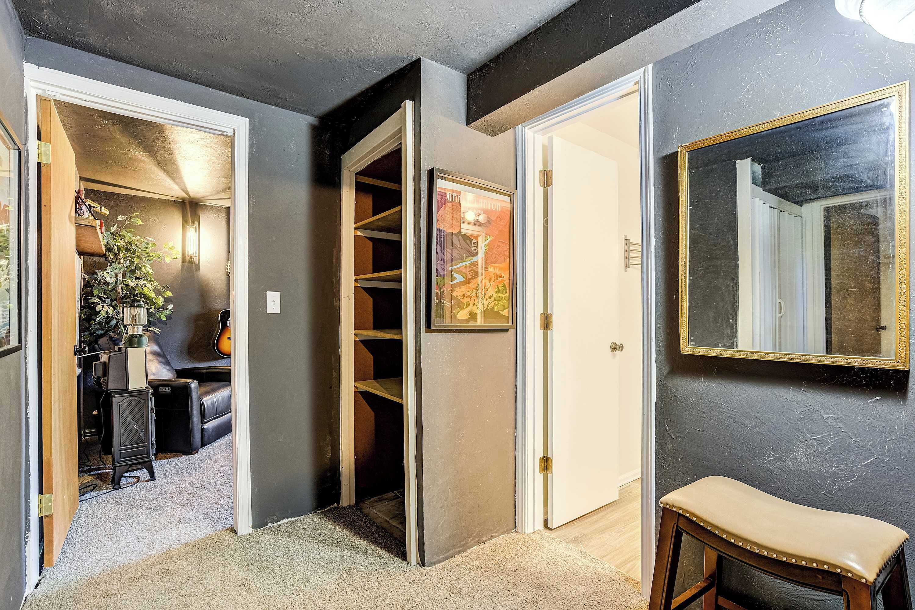 A hallway with a closet, a mirror, and a door leading to another room.