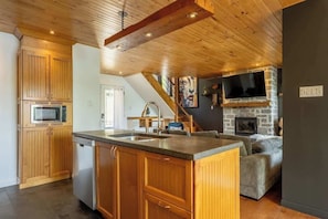 A kitchen with wooden cabinets, a built-in dishwasher, and a granite countertop. - La paix dans le Nord | Lac Brulé | SPA | SAUNA (Matawinie Regional County Municipality)