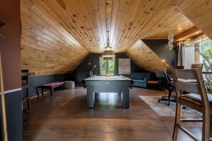 A room with a pool table, a sofa, and a chair. - La paix dans le Nord | Lac Brulé | SPA | SAUNA (Matawinie Regional County Municipality)