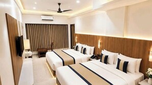 Una habitación de hotel con dos camas, un escritorio, una silla, un televisor y un ventilador de techo.