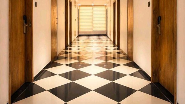 Un pasillo de hotel con piso a cuadros, puertas de madera y una lámpara en el techo.