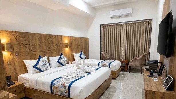 A hotel room with a large bed, a desk, a chair, and a television. - Fun Hotels Rajkot  (Rajkot)