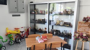 Un comedor con una mesa y sillas de madera, un aparador de cristal con objetos decorativos, y una bicicleta pequeña al fondo.