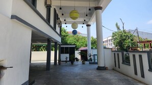 Un espacio al aire libre cubierto con varias columnas, luces colgantes y plantas en macetas.