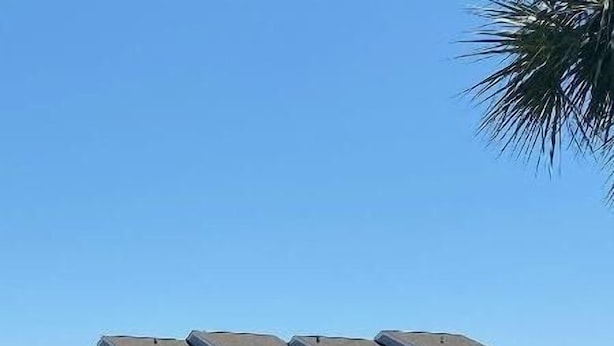 Un hotel de varios pisos con techo plano, balcones y un espacio al aire libre cubierto.